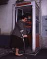 Persona con stampelle che cerca di entrare in una cabina telefonica