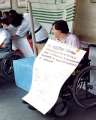 Persona disabile con cartellone e martellone